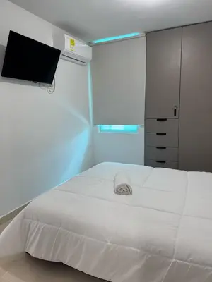 a bedroom with a white bed and a tv at Apartamento moderno en norte de la ciudad in Barranquilla
