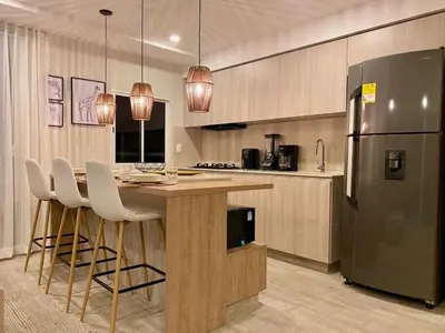 a kitchen with a island with chairs and a refrigerator at Exclusivo Apto En Dominique Cartagena in Cartagena de Indias