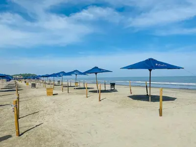 a row of blue umbrellas on a sandy beach at Spectacular Beachfront Apartment in Cartagena de Indias