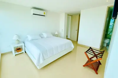 a white bedroom with a bed and a chair at Apartamento de Ensueño!! Sonesta Cartagena Salida Playa Vistas WOW Morros in Cartagena de Indias