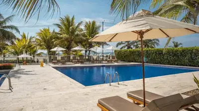 a resort swimming pool with an umbrella and chairs at Morros Ultra, Beachfront & 2 Bedrooms by Inmobiliaria MFR in Cartagena de Indias