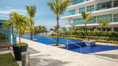 a swimming pool with palm trees in front of a building at Morros Ultra, Beachfront & 2 Bedrooms by Inmobiliaria MFR in Cartagena de Indias