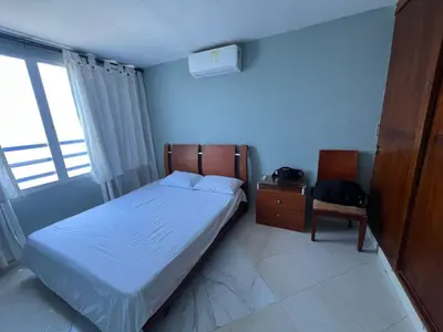 a bedroom with a bed and a chair and a window at Bahía Caribe in Estación El Salto