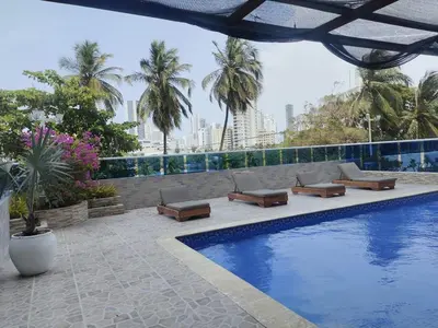 a swimming pool with lounge chairs and palm trees at Bahía Caribe in Estación El Salto