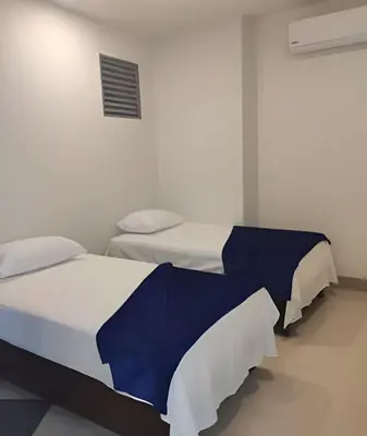 two beds in a white room with blue sheets at Apartamento en condominio de lujo morros eco. in Cartagena de Indias