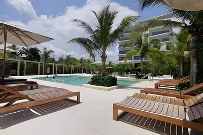 a pool with benches and palm trees and a building at Apartamento en condominio de lujo morros eco. in Cartagena de Indias