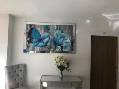 a painting of blue flowers on a wall with a table at Hostal Costacaribeam in Barranquilla