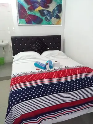 a bed with a red white and blue blanket at Hostal Costacaribeam in Barranquilla