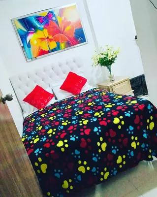 a bedroom with a bed with a black blanket with flowers at Hostal Costacaribeam in Barranquilla