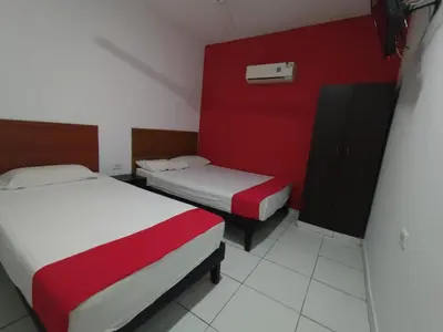 a room with two beds and a red wall at Hotel Madeleine Inn Sede Sur in Barranquilla