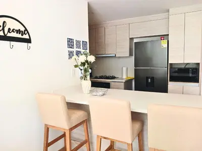 a kitchen with a counter with chairs and a refrigerator at Lujoso Apto con Piscina Privada y salida a playa in Cartagena de Indias