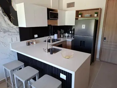 a kitchen with a sink and a counter with stools at Baia Kristal - Vacaciones Cartagena Colombia in Cartagena de Indias