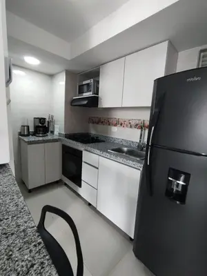 a kitchen with a black refrigerator and white cabinets at Sol y Brisa 811 in Cartagena de Indias