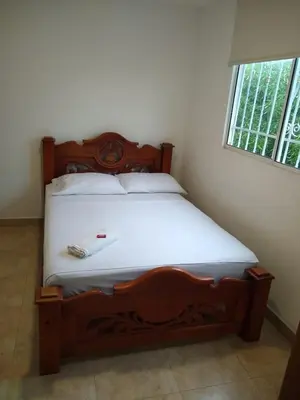 a wooden bed in a room with a window at Casa Hotel Marly in Santa Marta