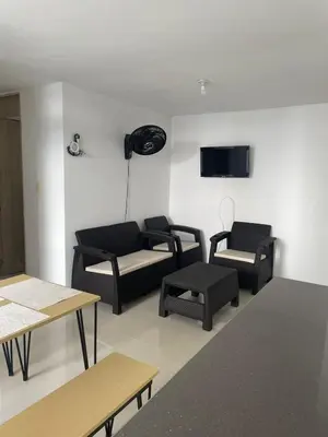 a living room with black furniture and a flat screen tv at Vacaciones Inolvidables in Coveñas