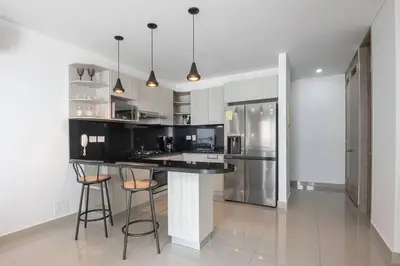 a kitchen with a black counter and two stools at Apartment With Beautiful View In Infinitum in Cartagena de Indias