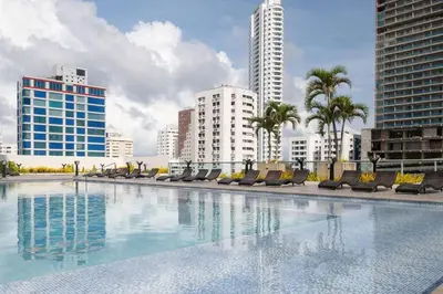 a large swimming pool with chairs and buildings at Apartment With Beautiful View In Infinitum in Cartagena de Indias