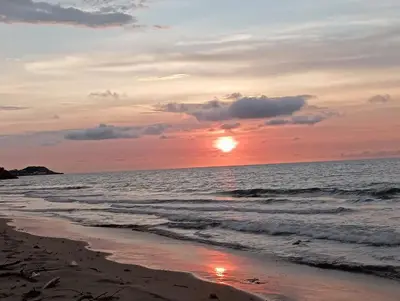 a sunset on a beach with the ocean at Habitaciones frente al mar in Carretal