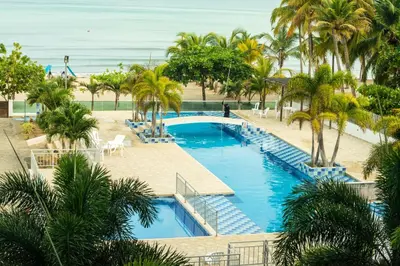 an aerial view of a resort pool with palm trees and the ocean at Magico Apartamento Frente al Mar 3 Habitaciones AR134 in Coveñas