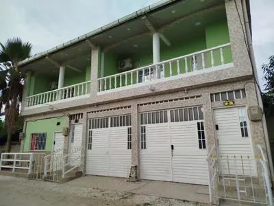 a building with three garage doors and a balcony at Apartamentos el farol in Ciénaga