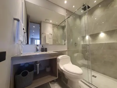 a bathroom with a toilet and a glass shower at Moderna suite con balcón y vista al lago y al mar in Cartagena de Indias