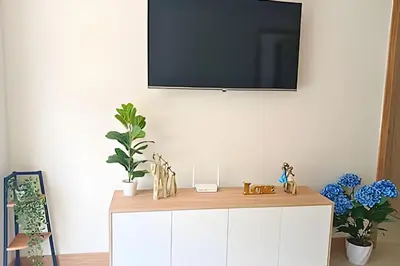 a tv on top of a white cabinet with plants at “Lujoso Apto con Piscina, Terraza Privada y Salida a la Playa” in Cartagena de Indias