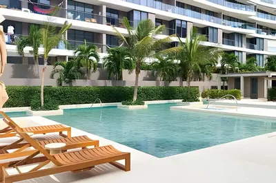 a swimming pool with chairs and a building at “Lujoso Apto con Piscina, Terraza Privada y Salida a la Playa” in Cartagena de Indias