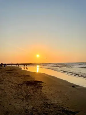 a sunset on a beach with people walking on the sand at Open Sea Hotel Cartagena - Frente al mar in Cartagena de Indias