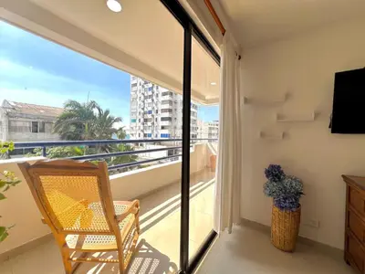 a room with a balcony with a chair and a television at Luxury mediterranean Suite in Cartagena de Indias