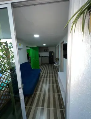 a living room with a blue couch and a kitchen at La Boquilla Oasis - Charming 1-Bedroom Apartment with Pool in Cartagena de Indias