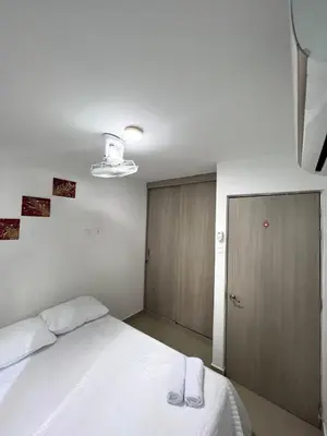a bedroom with a white bed and a wooden door at Exclusivo apartamento art zona norte in Cartagena de Indias