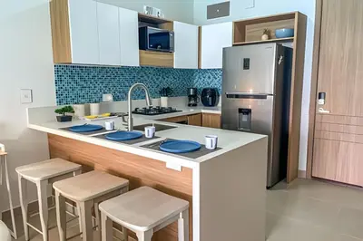 a kitchen with a counter with stools and a refrigerator at 1 Alcoba Hermosa vista a la laguna + bote inflable in Los Arrayanes