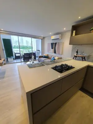 a kitchen with a counter top and a living room at Apartamento con balcón y vista al lago in Cartagena de Indias