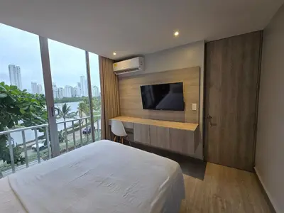 a bedroom with a bed with a television and a balcony at Apartamento con balcón y vista al lago in Cartagena de Indias