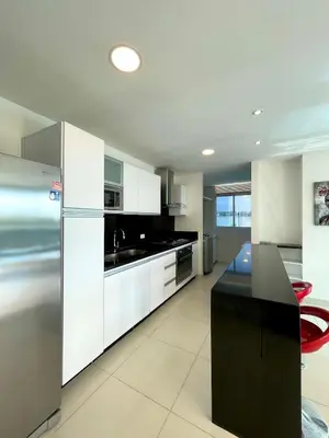 a kitchen with white cabinets and a black counter top at Lujo y espacio Bello Horozonte gran apartamento hasta 10 personas in Santa Marta