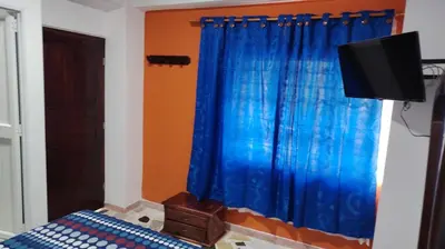 a bedroom with a blue curtain and a television at CARTAGENA BOQUILLA BEACH HOSTEl in Cartagena de Indias
