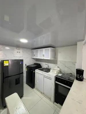 a kitchen with a black refrigerator and white cabinets at Edificio frente a la playa en cartagena, marbella in Cartagena de Indias