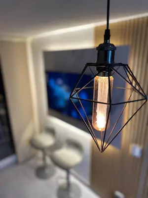a hanging lamp with stools in front of a television at Apto moderno, Vista al mar, 3Hab cerca de la playa in Cartagena de Indias