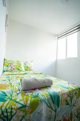 a bed with a colorful blanket and a window at Apto moderno, Vista al mar, 3Hab cerca de la playa in Cartagena de Indias