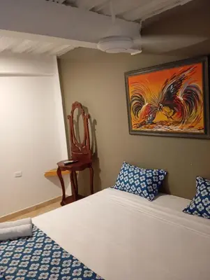 a bedroom with a bed and a chair and a painting at Hotel Nativo Manzanillo in Cartagena de Indias