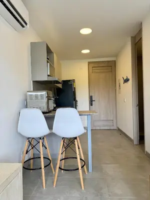 a kitchen with two white stools and a counter at Elemnt Rentals in Santa Marta