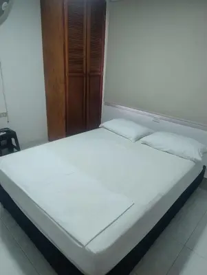 a white bed in a room with a wooden cabinet at Casa Turistica Parador Verona in Cartagena de Indias