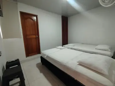a bedroom with two beds and a wooden door at Casa Turistica Parador Verona in Cartagena de Indias