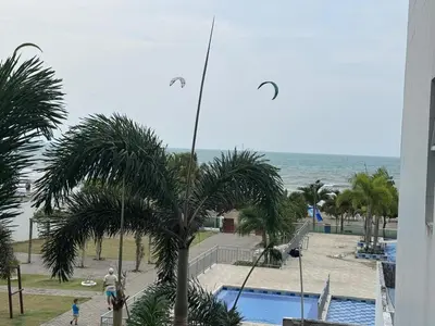 a view of a resort with a palm tree and the ocean at Apartamentos Mi Reserva OK - Arrecife in Coveñas