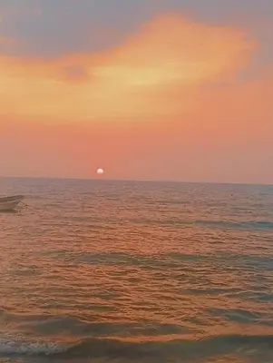 a sunset over the ocean with a boat in the water at Los Clemones in Rincón