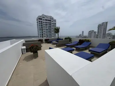 a rooftop patio with blue lounge chairs on a building at Apartamento con vista al mar - Piscina en la azotea - 2 habitaciones + 2 baños in Cartagena de Indias