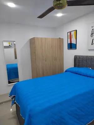 a bedroom with a blue bed and a wooden cabinet at Espectacular apartamento amoblado en BARRANQUILLA in Barranquilla