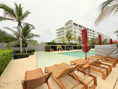 a pool with lounge chairs and a red umbrella at Espectacular apartamento con piscina privada - Morros Zoe in Cartagena de Indias