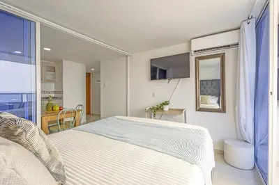 a white bedroom with a bed and a window at Riviera Coral Beach - Con vista al mar in Cartagena de Indias
