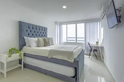 a bedroom with a large bed with a blue headboard at Riviera Coral Beach - Con vista al mar in Cartagena de Indias
